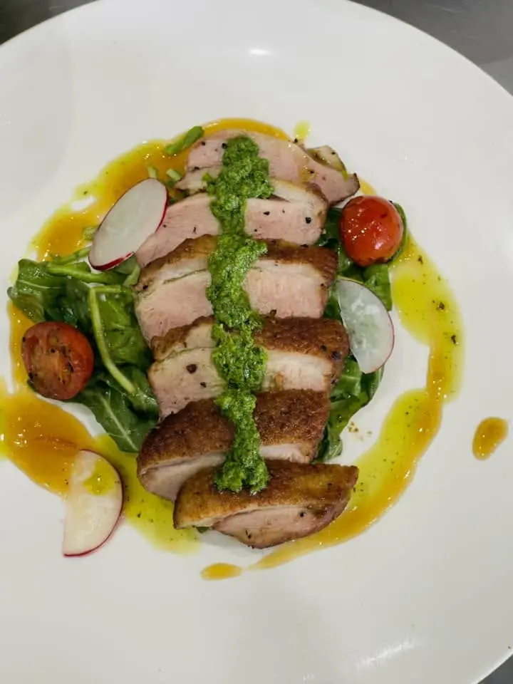 Sliced duck breast with pesto and heirloom tomato